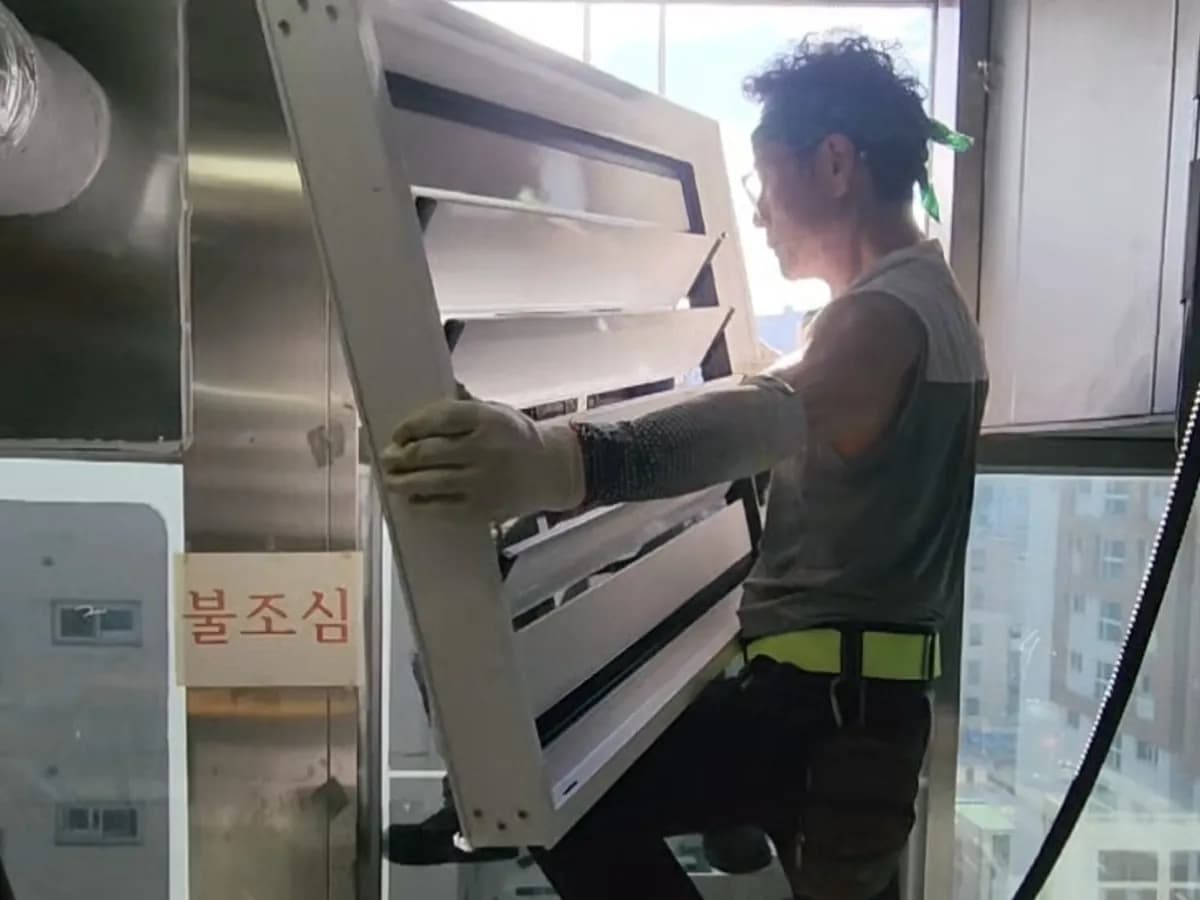 실외기실 창에 루버창을 끼워 넣는 작업자