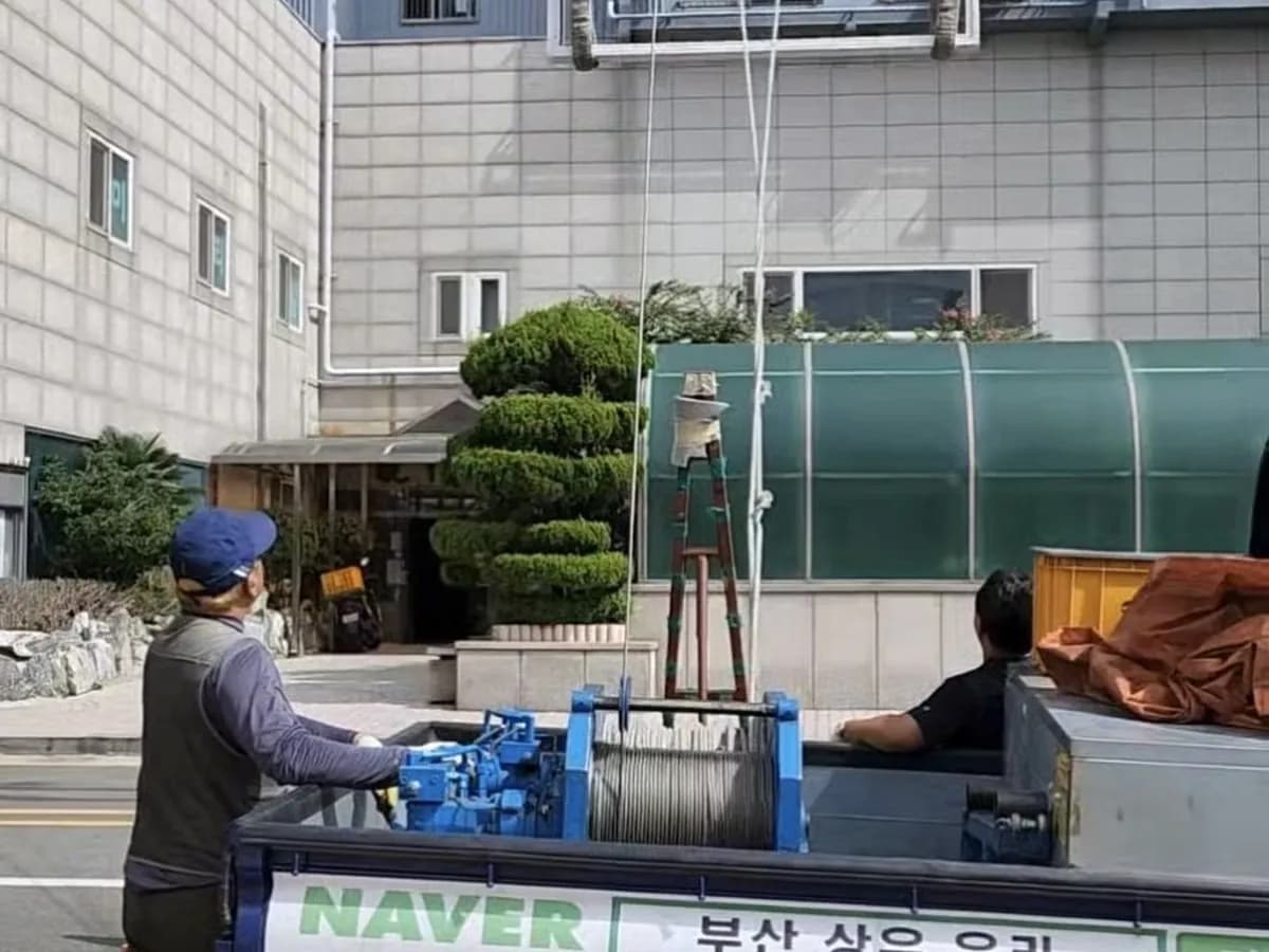 상우유리 트럭 짐칸의 유압윈치와 줄을 잡은 작업자